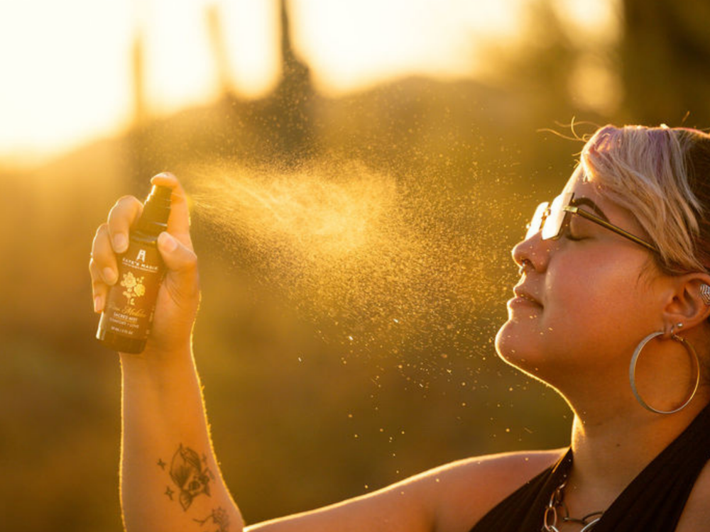 Spraying a Kate’s Magik Aura Mist with golden light in the background