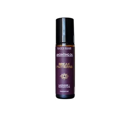 A bottle of Kate's Magick 'Break Patterns' anointing oil, featuring a dark purple label with gold and white text, and a black cap, set against a plain white background.