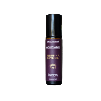 A bottle of Kate's Magik Anointing Oil, Venus - A Love Oil Cardamom and Ylang Ylang, featuring a dark purple label with gold lettering and a black cap, set against a plain white background.
