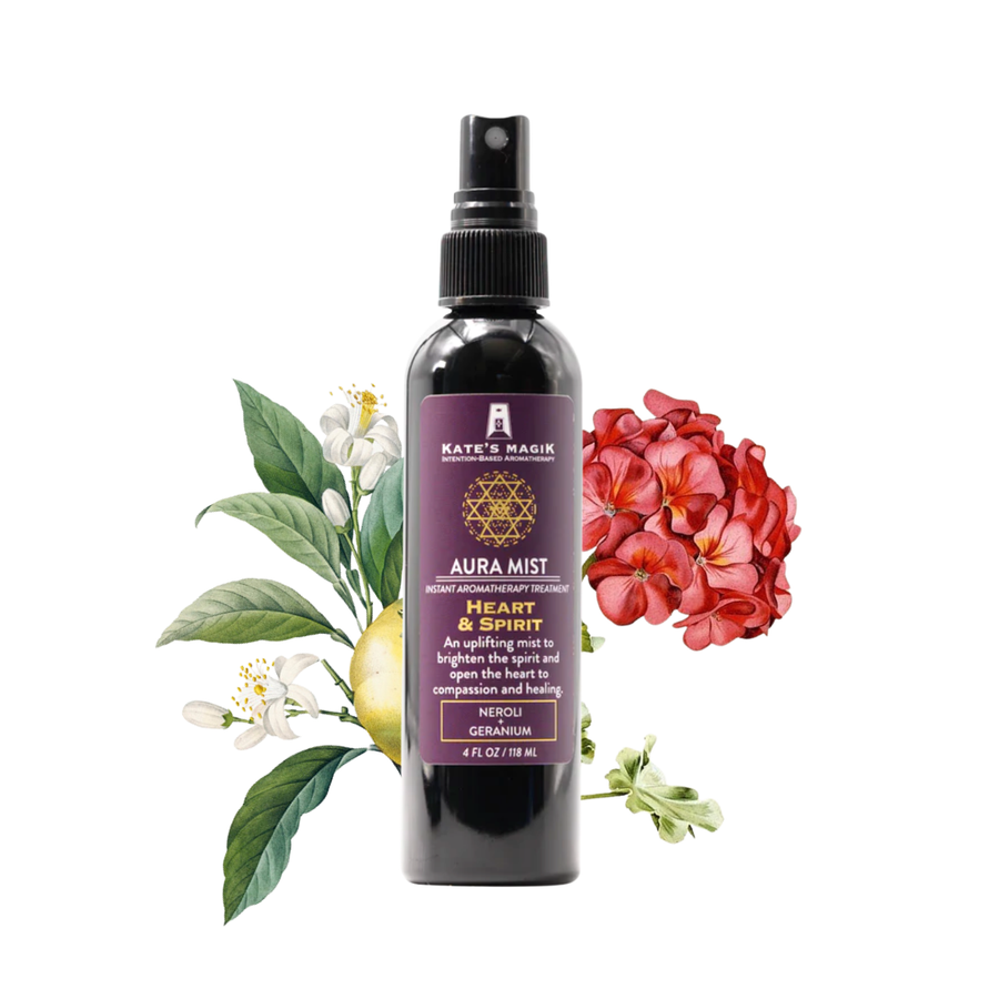 A 4oz bottle of Kate's Magik Heart and Spirit Aura Mist featuring a black spray top and a dark purple label with gold text and a geometric symbol, styled with green leaves, white flowers, a yellow citrus slice, and red flowers on a solid white background. 
