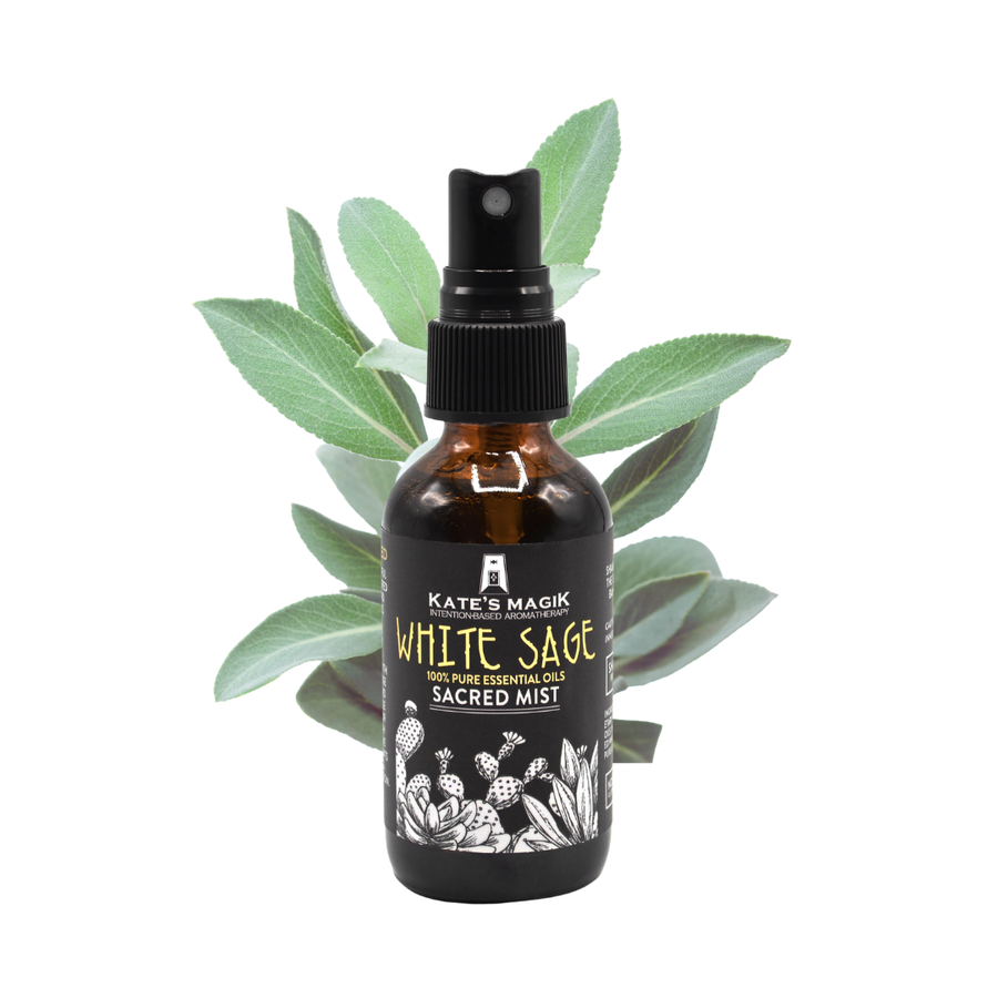 A bottle of Kate's Magick White Sage Sacred Mist essential oil spray, shown with green sage leaves behind it on a solid white background.