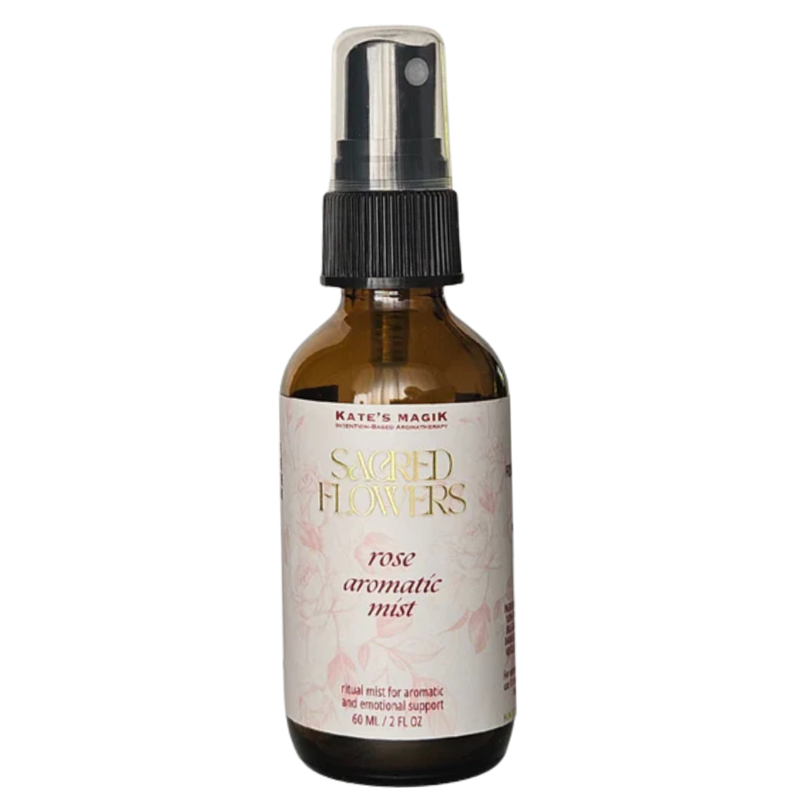 A 2 fl oz amber glass spray bottle of Kate's Magik Sacred Flowers Rose Aromatic Mist with a black spray nozzle and a white label with pink floral accents, set against a plain white background.