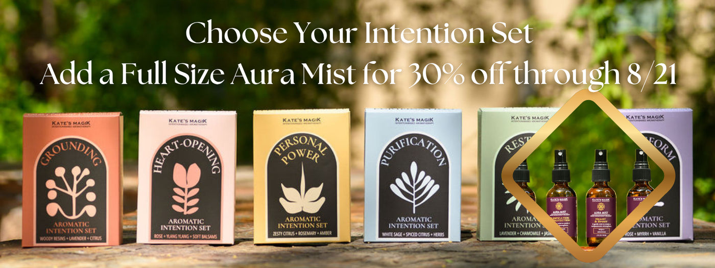 Six boxed intention sets from Kate Magik are lined up on a wooden surface outdoors, with large promotional text above reading 'Choose Your Intention Set' and 'Add a Full Size Aura Mist for 30% off through 8/21.' The boxes are labeled Grounding, Heart-Opening, Personal Power, Purification, and Restore, and Transform, with an inset photo of aura mists amber bottles with fine mist sprayer caps.
